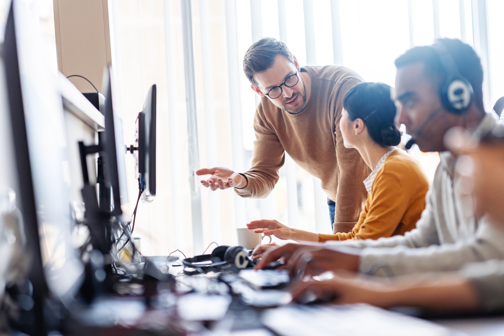 Multiethnic group of IT profesionals working togeter using computers in their office